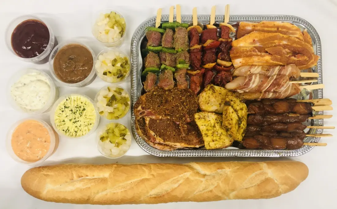 Een barbecuemenu van B&G Catering: spiesen, worst en gemarineerd vlees op een schaal