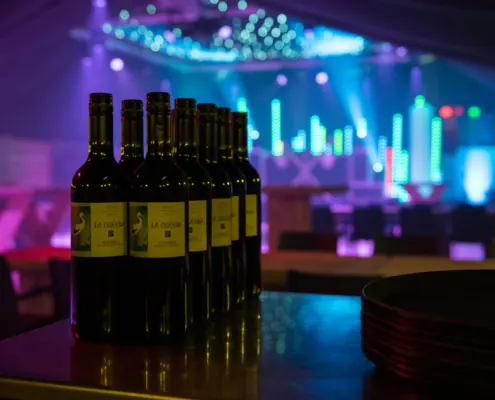 Flessen wijn en borden klaargezet in een feestzaal met sfeerverlichting