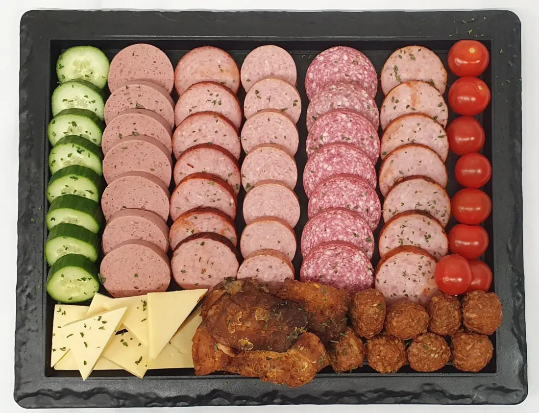 Een opgemaakte schaal met vleeswaren, kaas, komkommer en tomaatjes